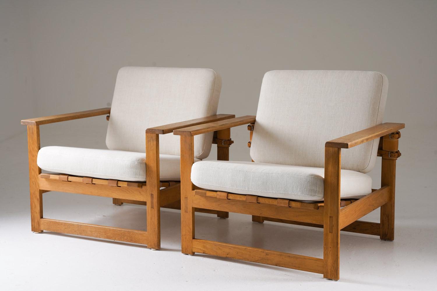 Very rare Swedish lounge chairs in oak with linen cushions and leather accents, designed by Nils Roth in the 1960s. These chairs embody the clean, functional lines of Scandinavian design, with solid oak frames that offer both durability and